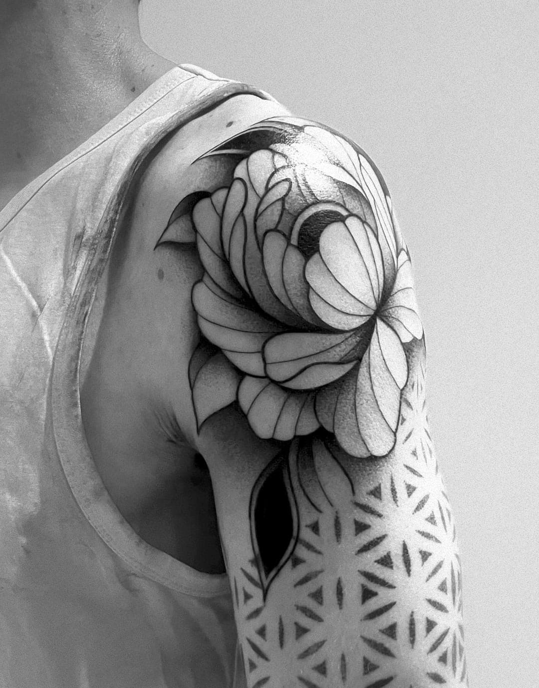 Black and grey peony tattoo on a shoulder by Romain Noiry