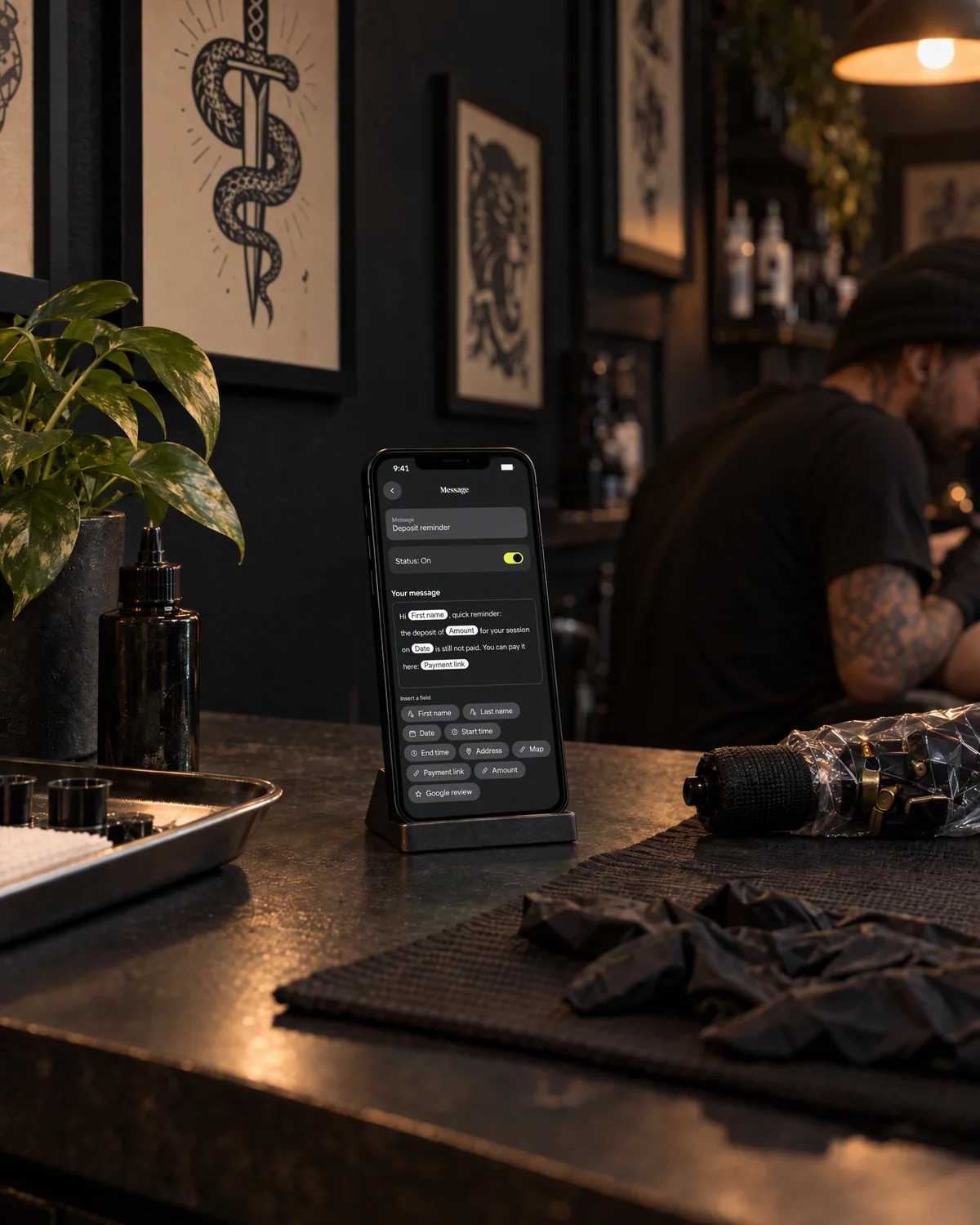 Staged photo: the needlz deposit message on an iPhone, next to a tattoo machine