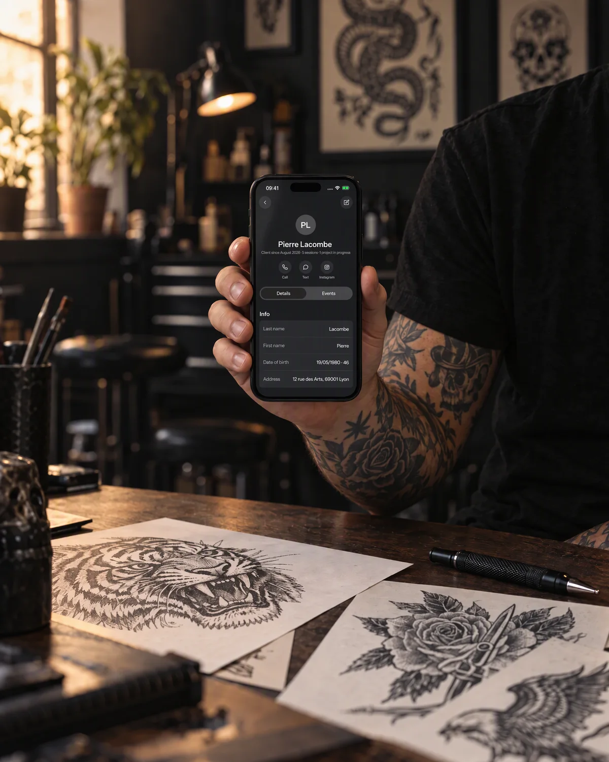 Staged photo: a client record in needlz, on an iPhone held by a tattoo artist